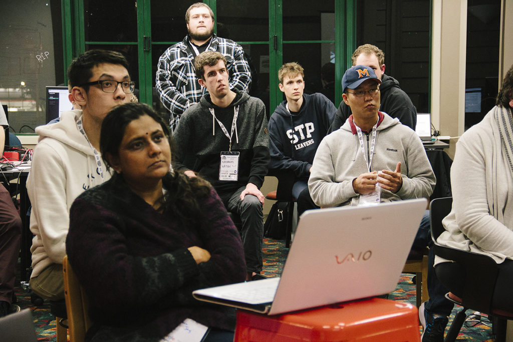 A group of people, all staring off camera, looking at a presentation